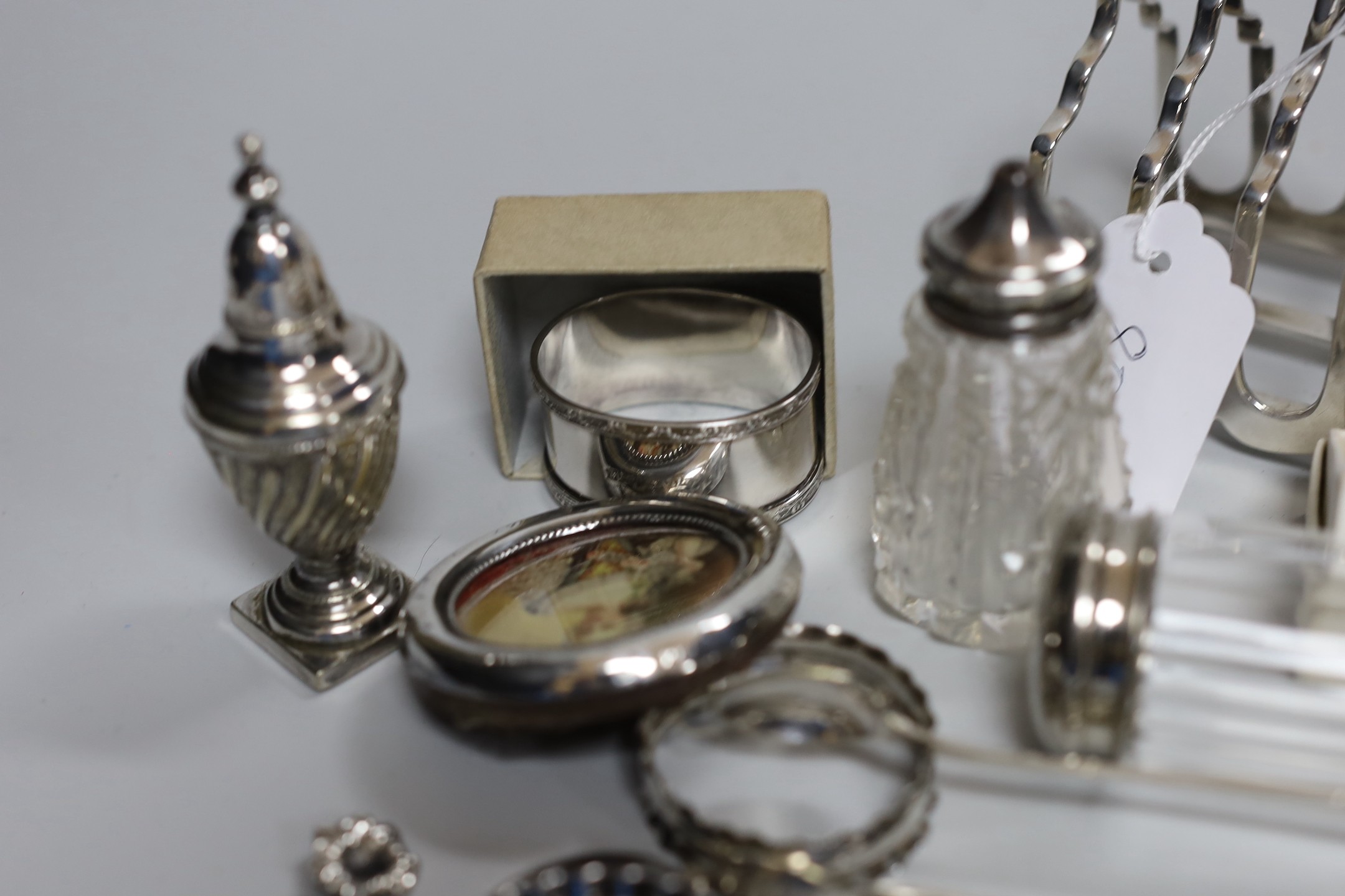 Assorted minor silver ware including a George V toast rack by James Dixon & Sons, 86mm, two napkin rings, a mounted glass toilet jar and condiment, pair of sugar tongs, a fruit knife, a commemorative spoon, a mounted sma